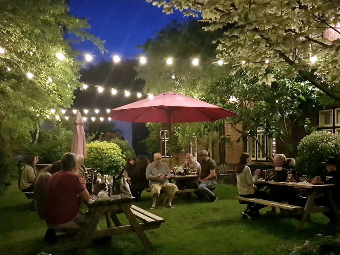 Guests in the pub garden under festoon lights