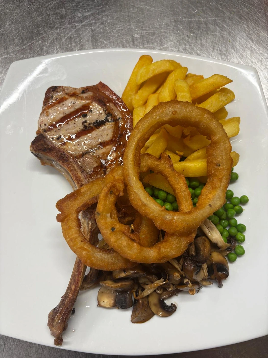 Steak, chips, onion rings and peas